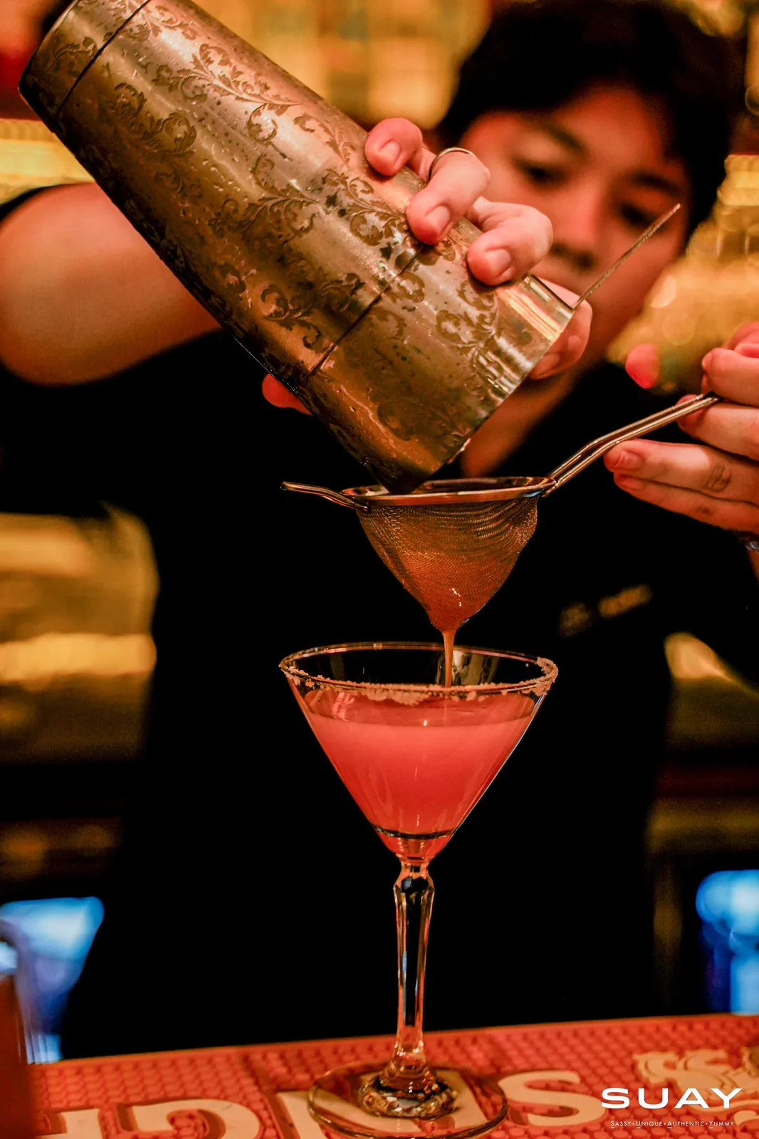 Pink cocktail being strained